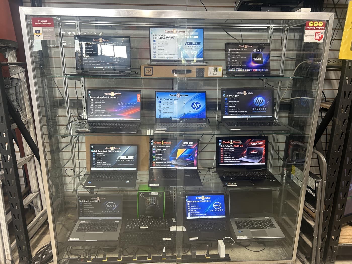 Used laptops displayed in the electronics case at Cash 1 Pawn
